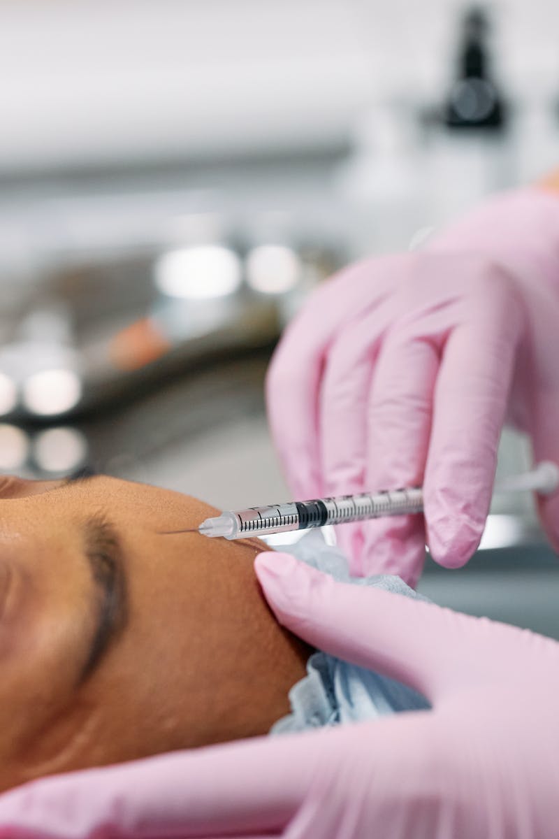 Mãos de médica aplicando botox em testa de paciente - Metrópoles