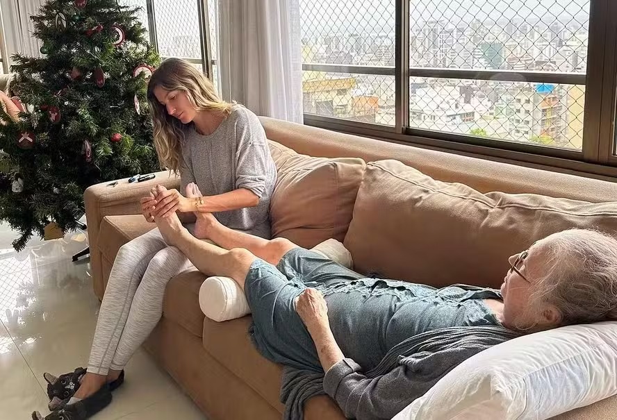 Gisele Bündchen massageia os pés da mãe