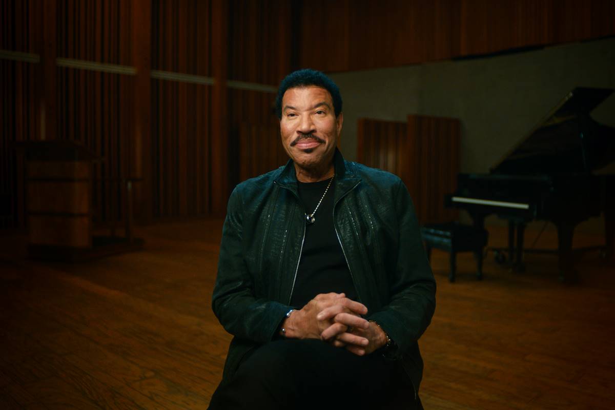 Lionel Richie de terno sentado em um estúdio - Metrópoles