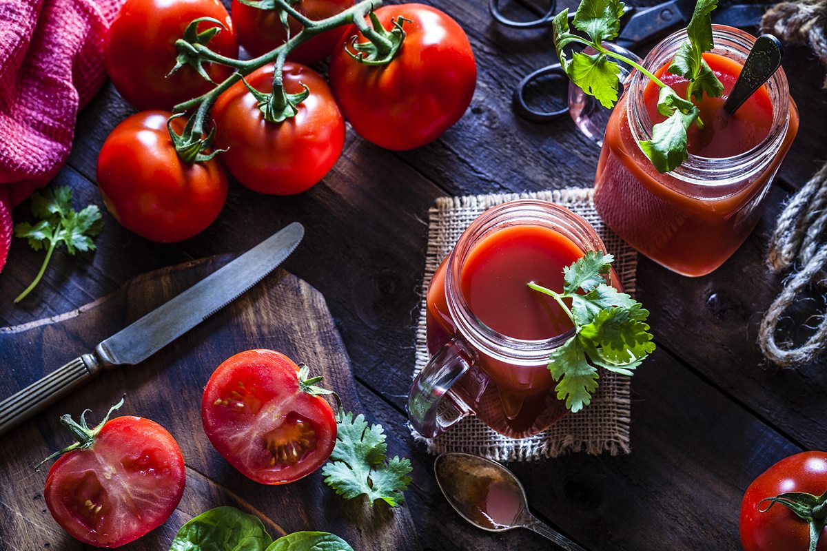 Imagem mostra vista superior de uma mesa com vários tomates e dois copos de suco vermelho - Metrópoles