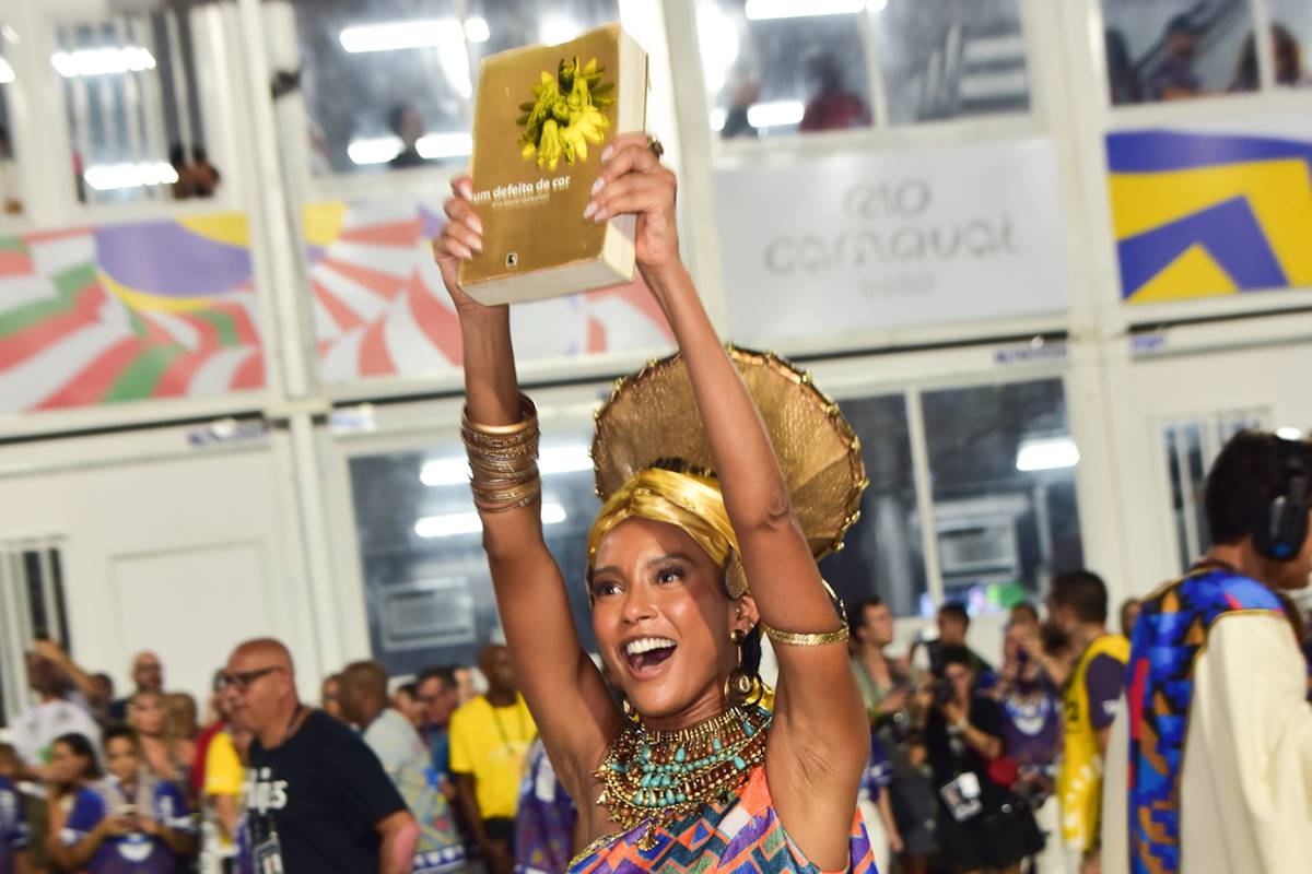 Taís Araújo carregando o livro Um Defeito de Cor na Sapucaí, durante desfile da Portela - Metrópoles