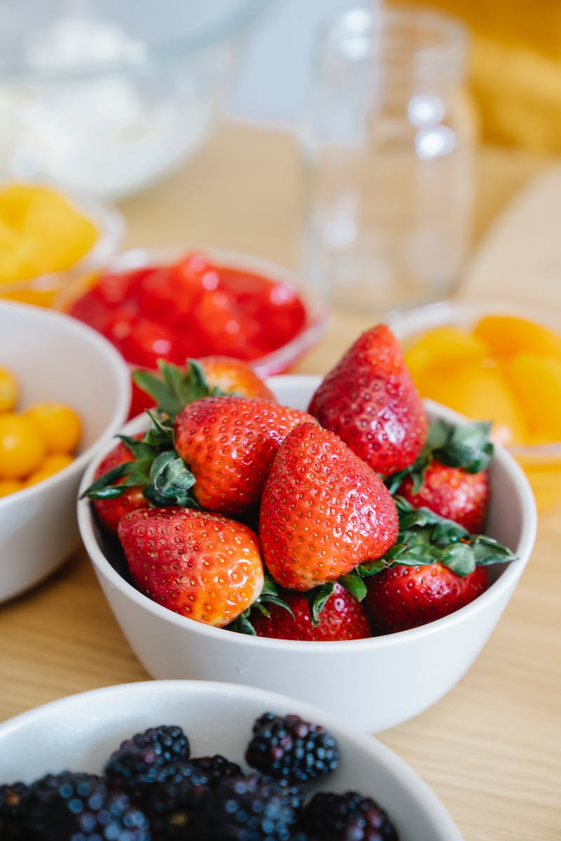 Recipientes brancos com morangos e outras frutas ao redor - Metrópoles