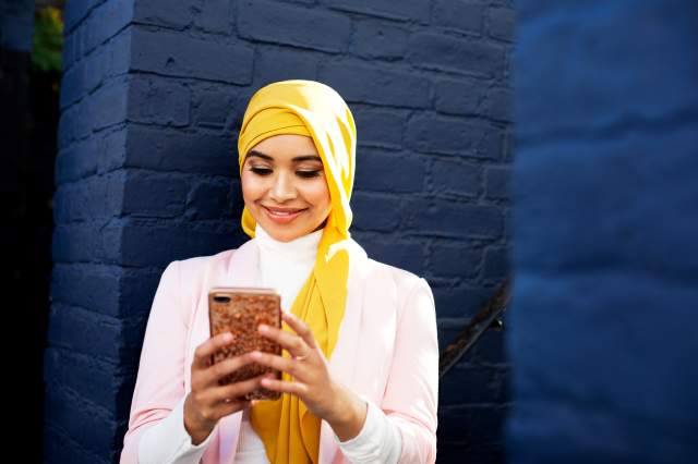 Na imagem com cor, uma mulher com hijab mexendo no celular - Metrópoles