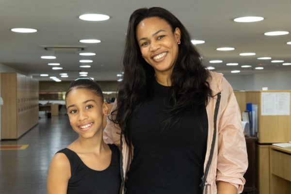 foto colorida de uma menina ao lado de uma mulher, ambas negras, com roupa preta - Metrópoles 