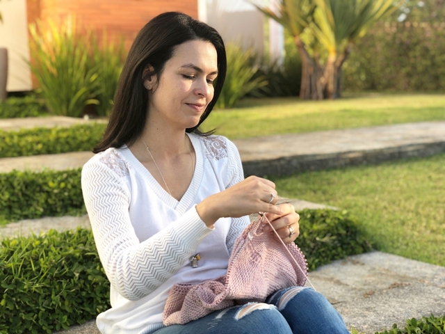 Viviane Basile: na imagem, ela está crochetando com fios rosa - Metrópoles