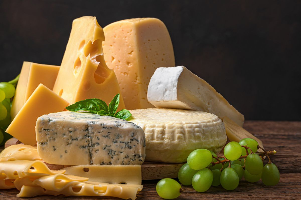 Foto colorida - Diferentes queijos em uma mesa 