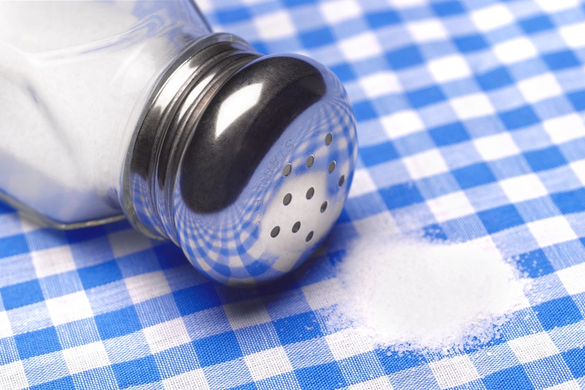 Saleiro deitado com um pouco de sal na mesa