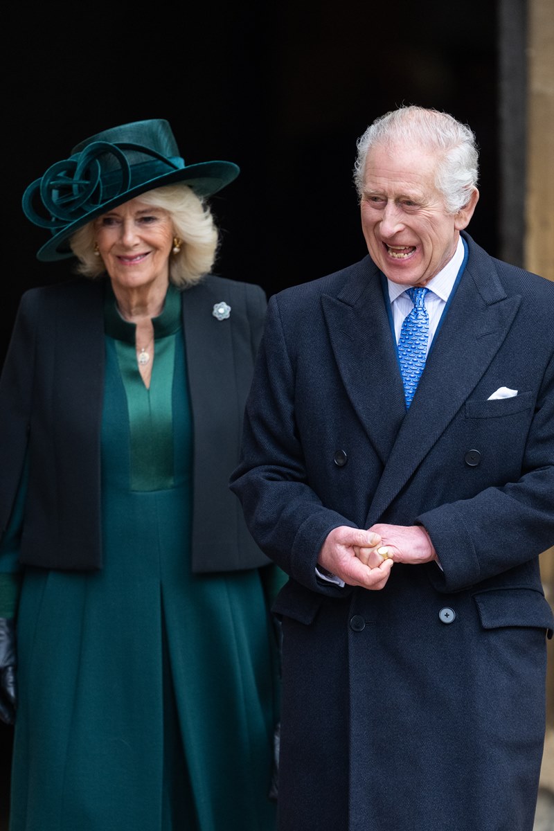 Foto de mulher idosa com roupa e chapéu verde ao lado de homem idoso com casaco longo preto - Metrópoles