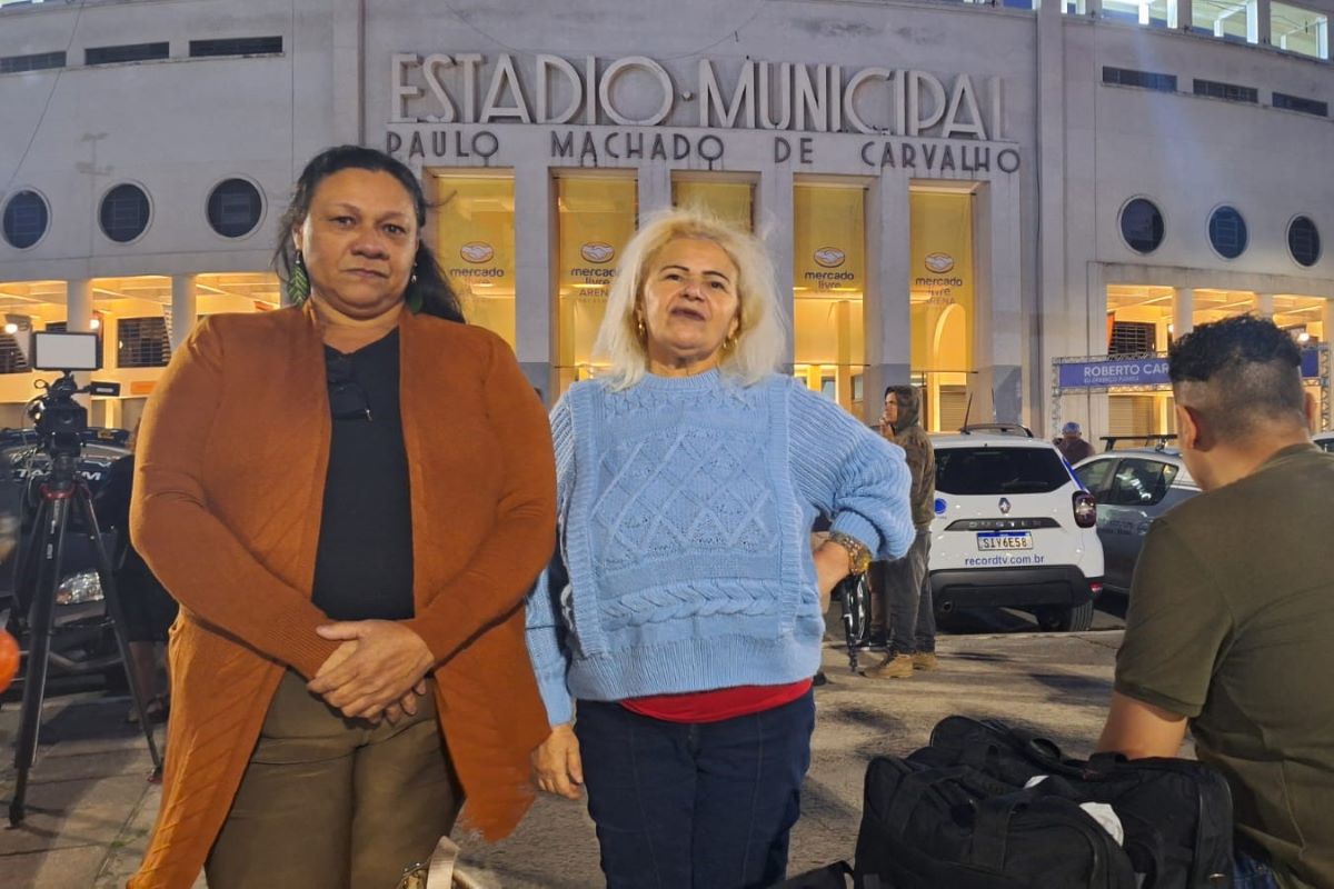 Imagem colorida de mulheres em pé a frente do Pacaembu. Metrópoles