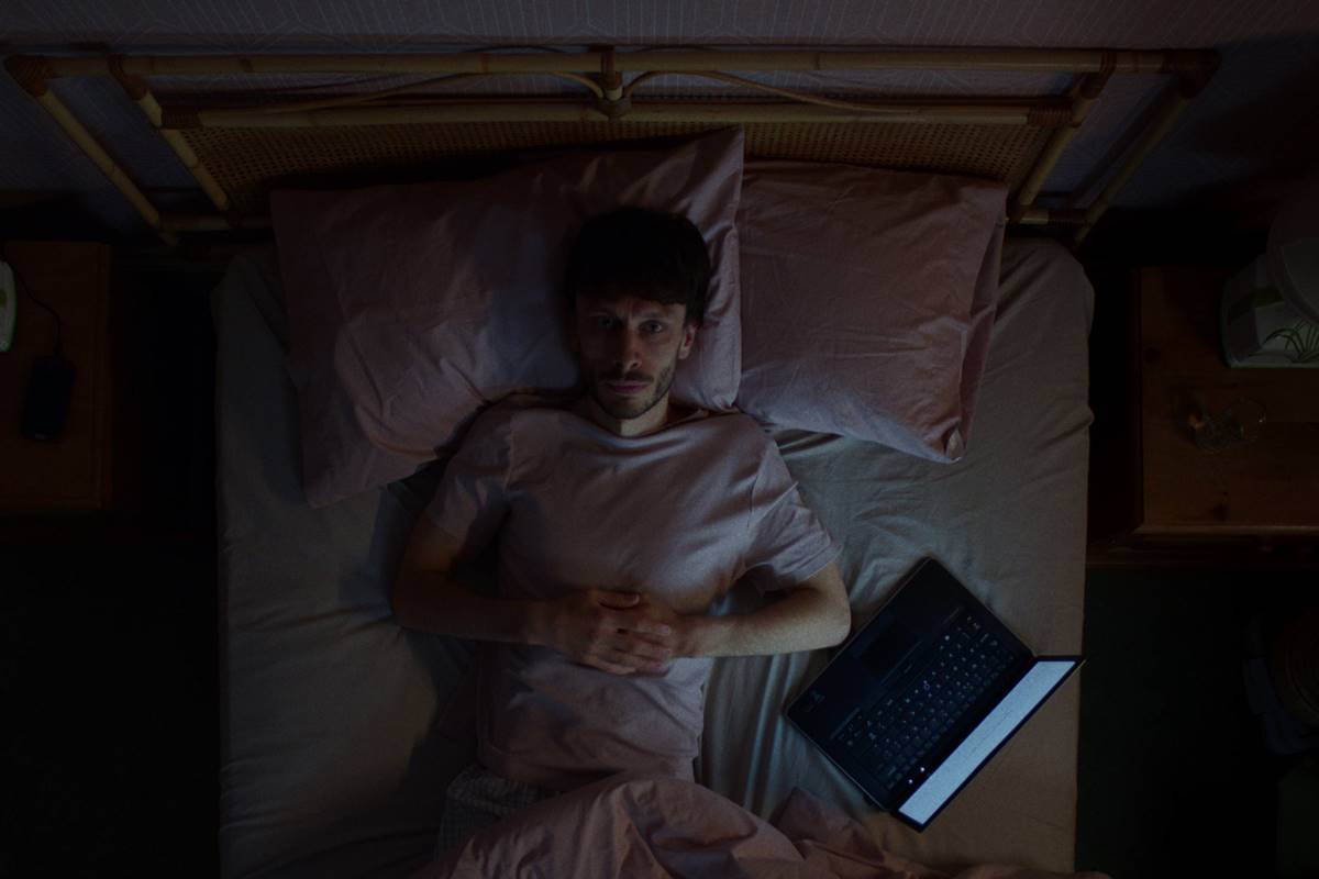 foto colorida de homem deitado em cama com notebook ao lado - metrópoles