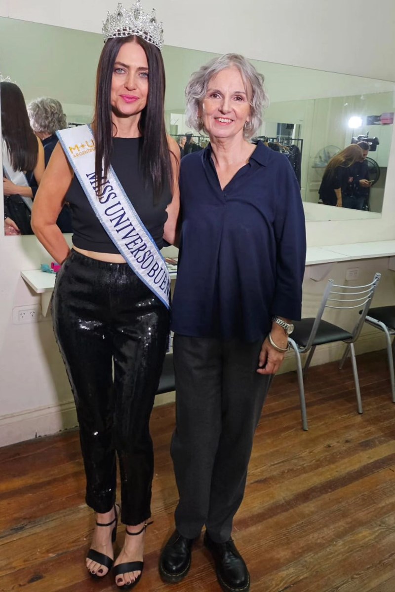 Foto colorida de mulher com coroa e faixa de miss abraçada a uma mulher idosa - Metrópoles