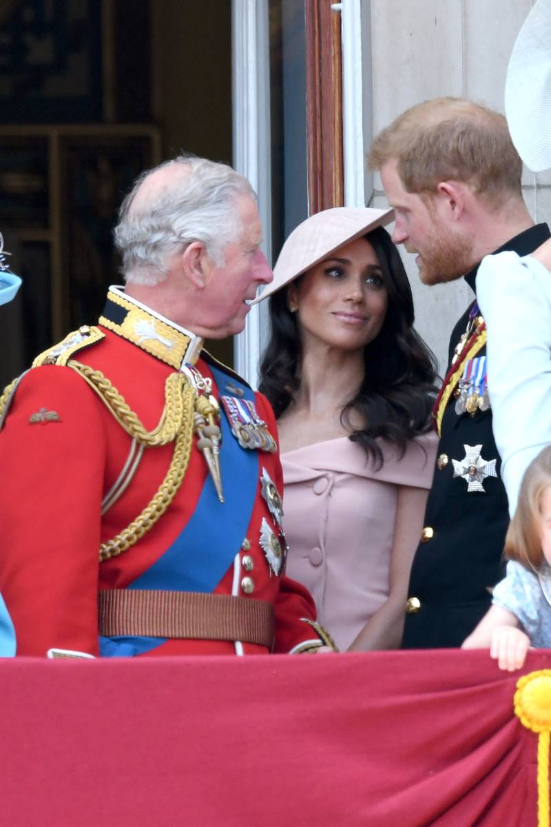 Foto colorida de mulher com roupa na cor rosé entre dois homens com trajes militares - Metrópoles