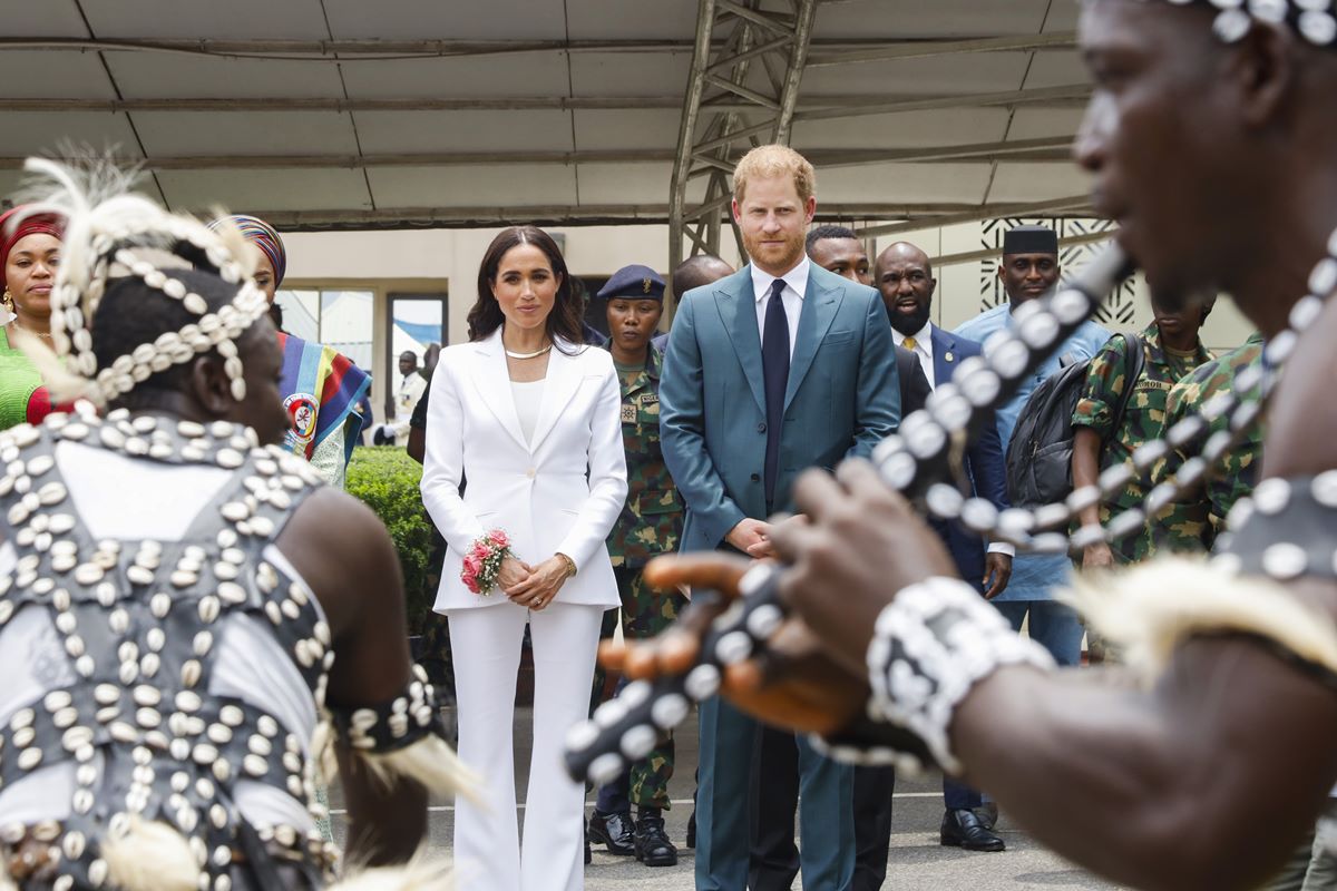 Foto colorida de mulher com terno branco e homem com terno azul assistindo à uma apresentação - Metrópoles