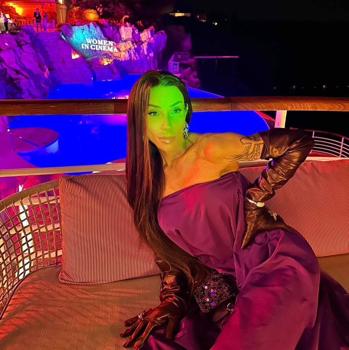 Maya Massafera posa, de vestido roxo e luva preta, no hotel onde em Cannes - Metrópoles
