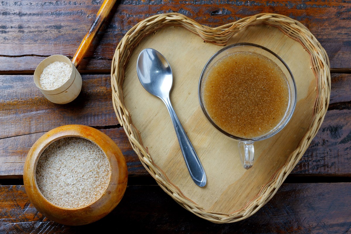 Fibra da casca de psyllium misturada com água no copo de vidro formando gel servida em uma bandeja de madeira em formato de coração