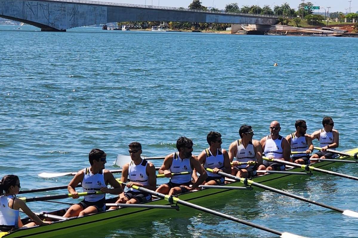 Foto colorida de grupo de pessoas remando em lago - Metrópoles