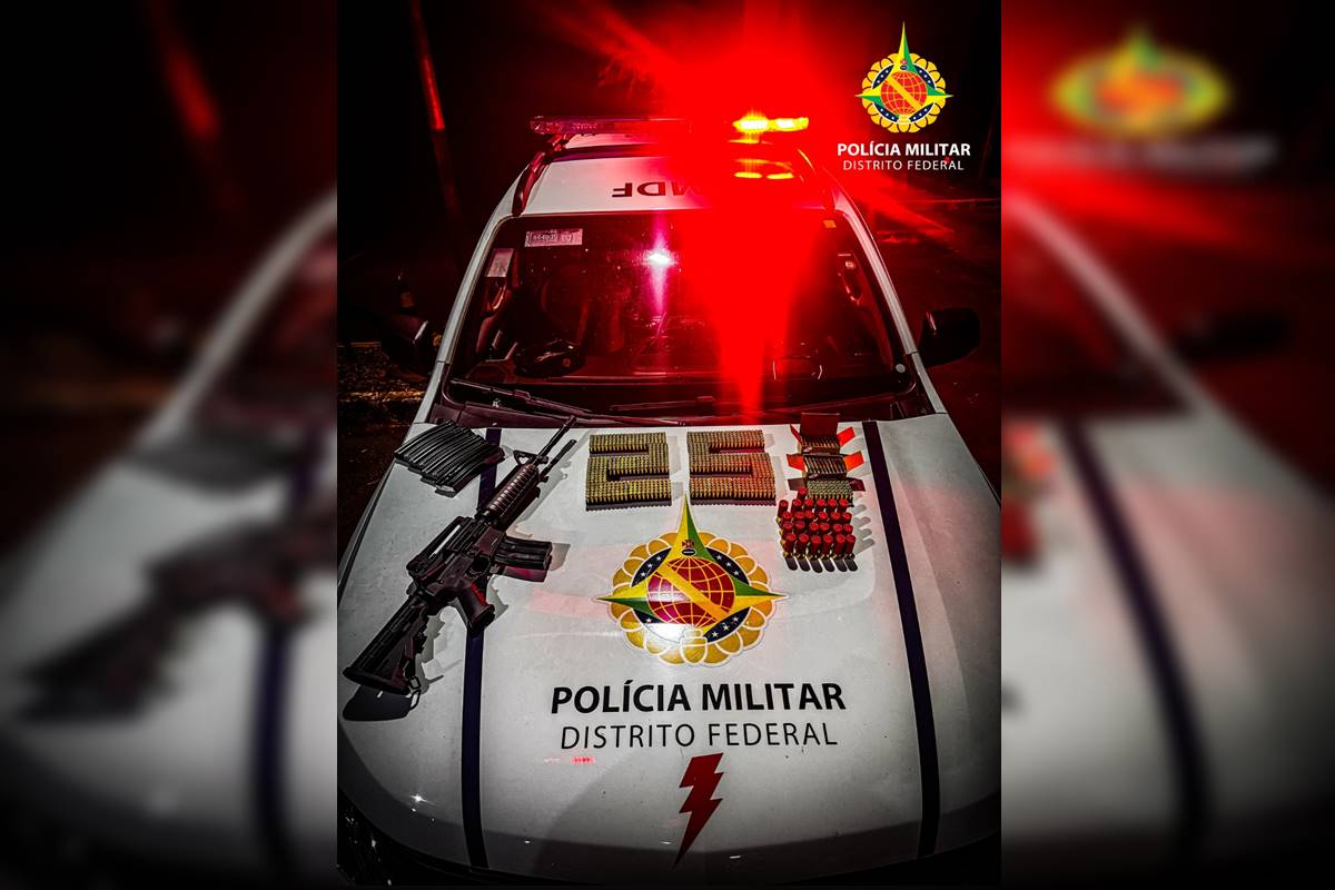 Foto colorida de fuzil e munições em cima de capo de carro de polícia