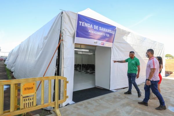 Fotografia colorida mostrando três pessoas entrando em tenda de acolhimento-Metrópoles