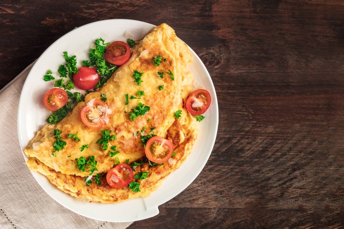Foto colorida - Omelete com tomates cerejas em um prato branco