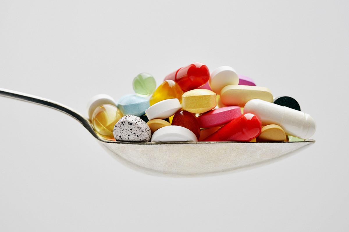 Foto colorida de colher com cápsulas de medicamentos - Metrópoles