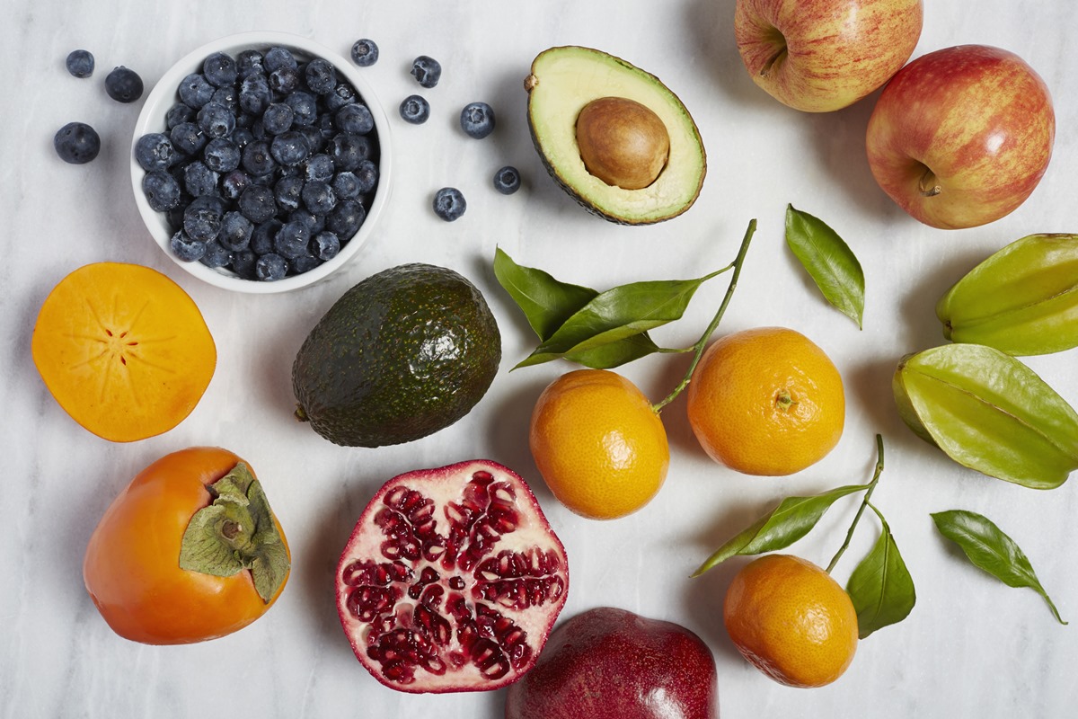 Frutas dispostas em um fundo branco: maçãs, abacate, laranja, romãs e mirtilos. - Metrópoles - Alzheimer - avocado