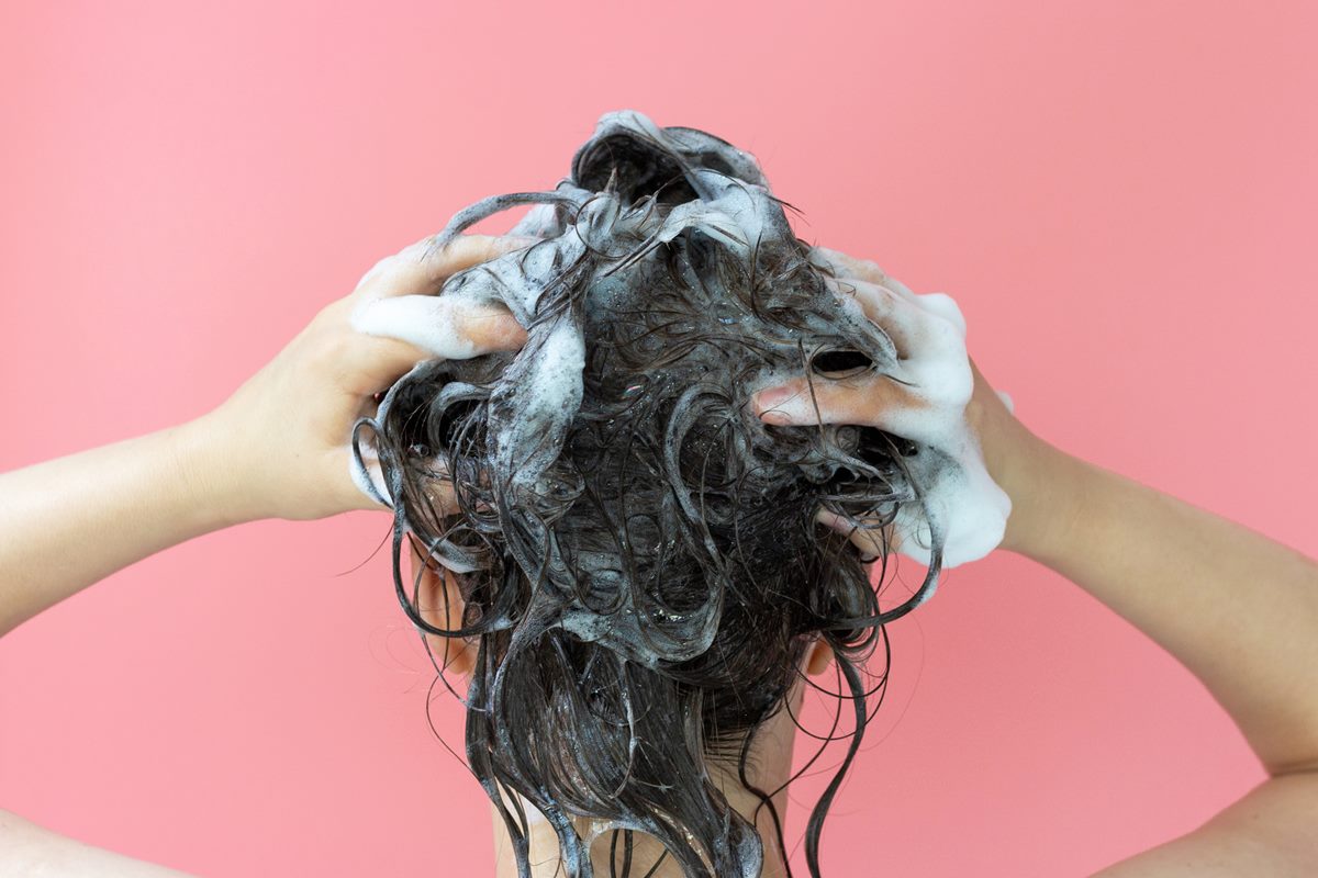Foto colorida de mulher lavando o cabelo - Metrópoles