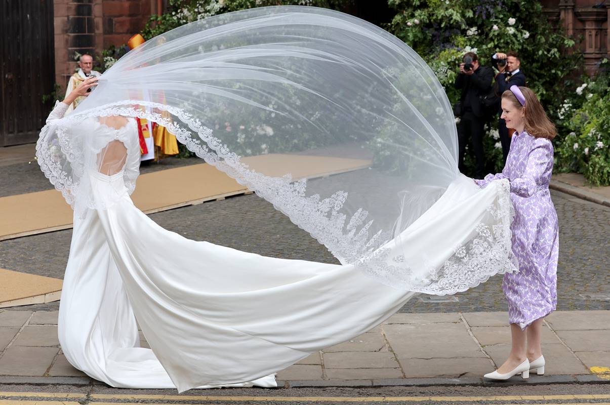 Foto colorida de mulher arrumando vestido e véu de noiva bagunçados pelo vento - Metrópoles