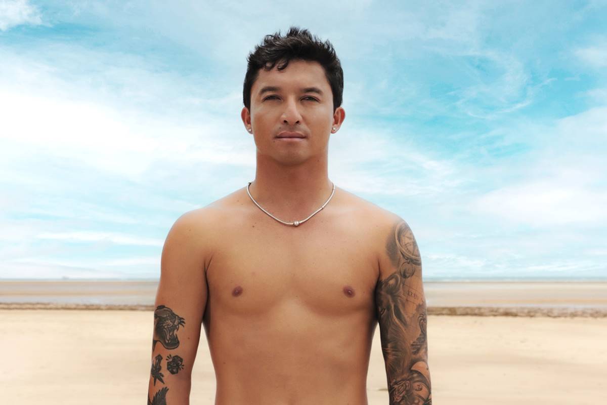 Na imagem colorida, homem posa sem camisa em praia - Metrópoles