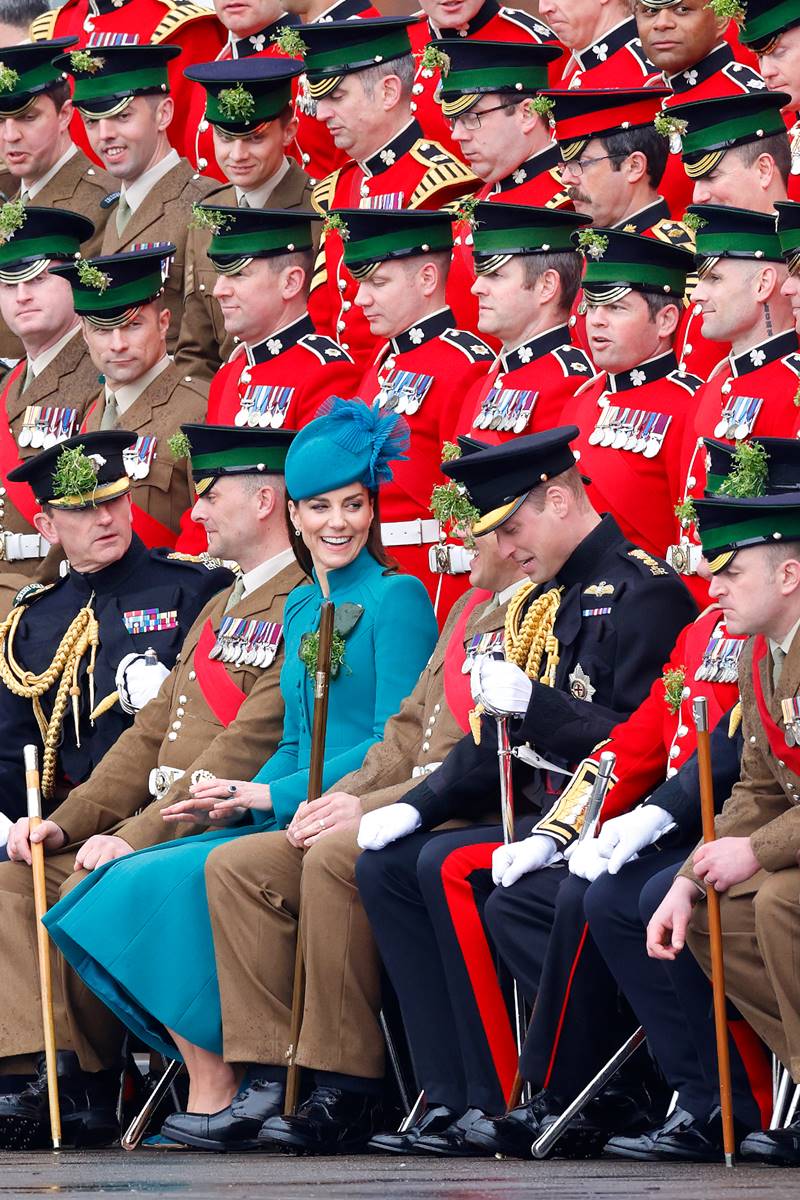 Foto colorida de mulher com vestido verde rodeada de homens com uniforme militar - Metrópoles