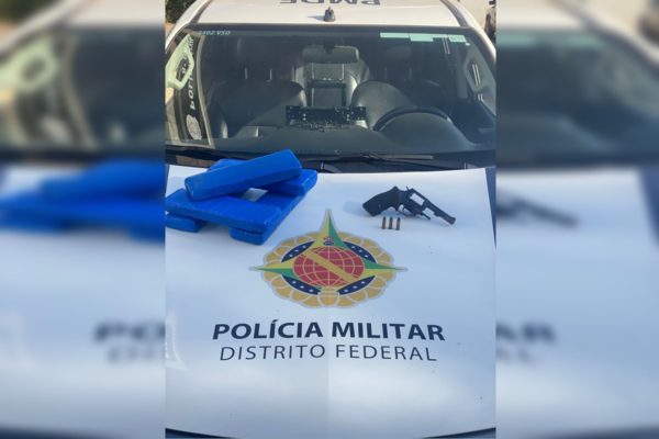 Foto colorida de carro de policia com arma e droga 