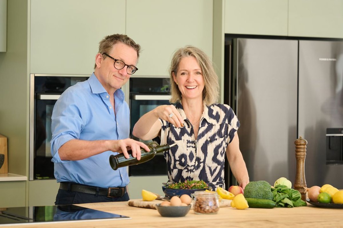 Foto colorida de homem e mulher em uma cozinha. Eles estão perto de vegetais - Metrópoles