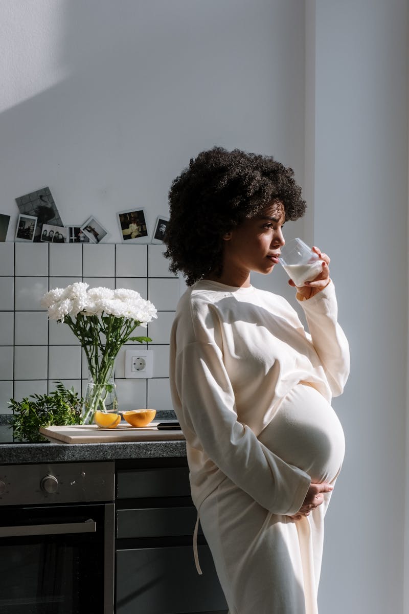 Jovem mulher negra grávida bebendo água - Metrópoles