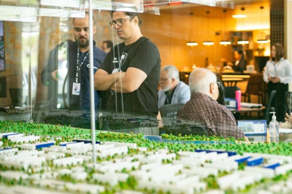 Fotografia colorida mostrando duas pessoas olhando maquete de prédio durante evento-Metrópoles