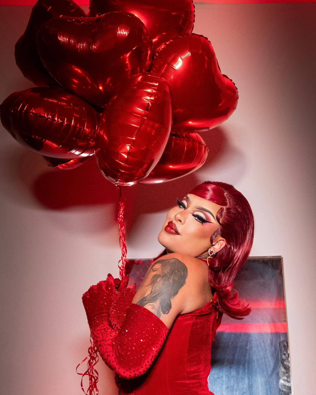 Gloria Groove com cabelos vermelhos segurando balões de coração - Metrópoles