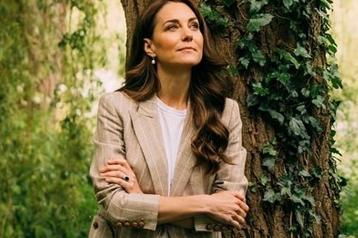 Foto colorida de mulher em um jardim. Ela está com os braços cruzados - Metrópoles