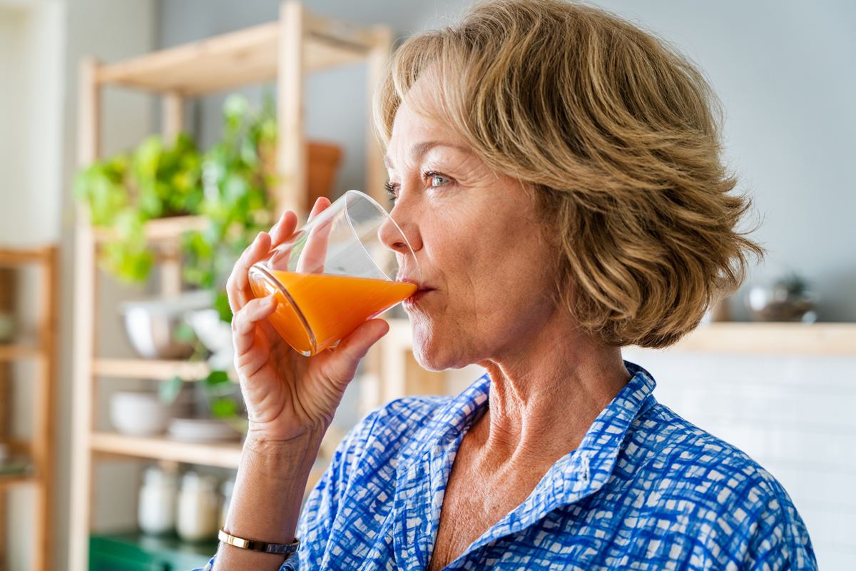 Foto colorida de mulher, de cabelo curto e blusa azul, tomando um suco - Metrópoles