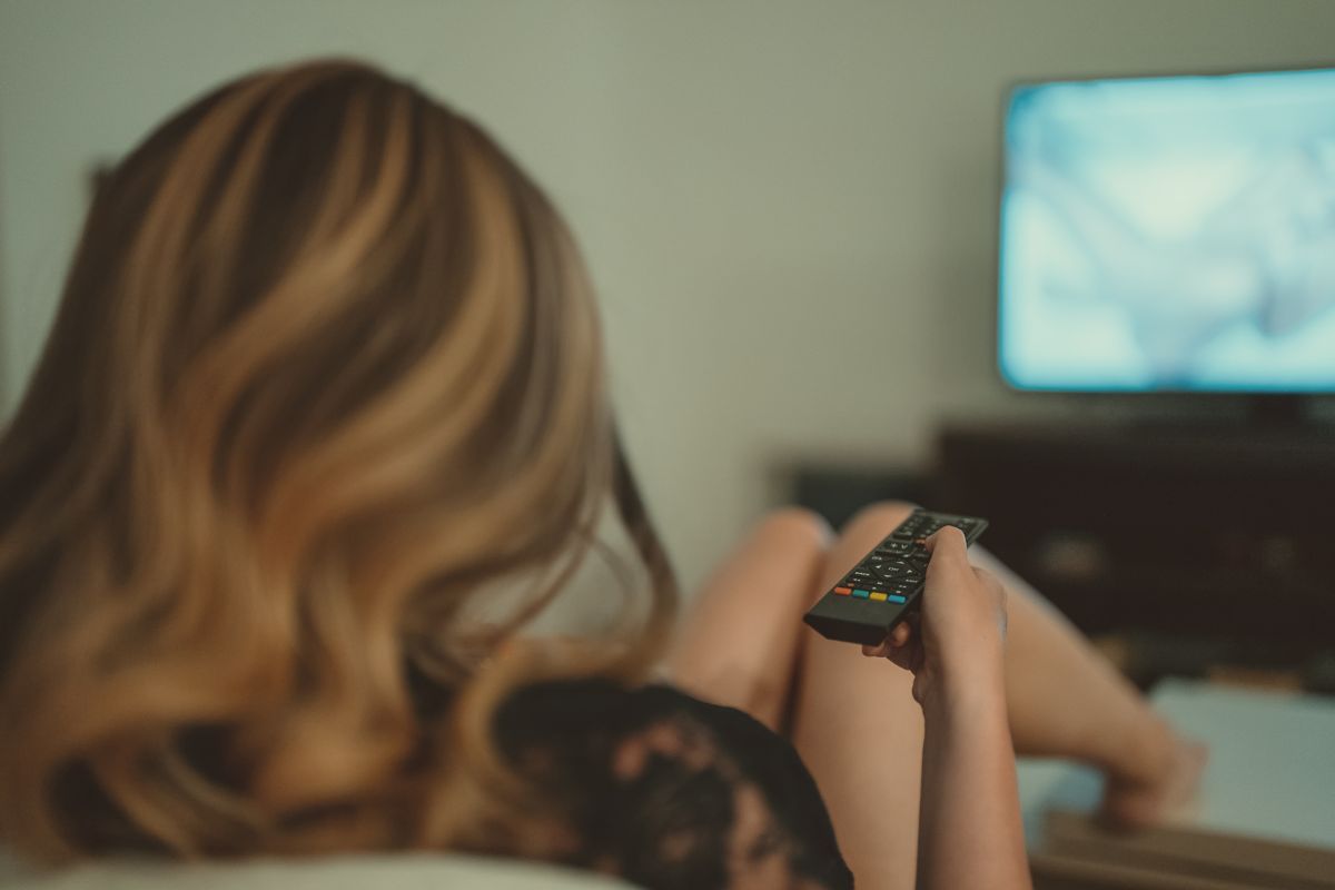 Foto colorida de uma mulher vendo TV - Metrópoles