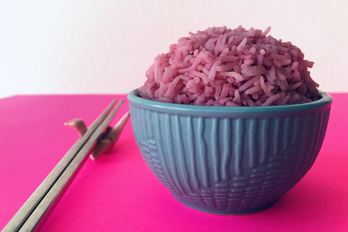 Foto colorida - Pote azul com um arroz rosa dentro, que tem uma aparência semelhante com o "arroz de carne" criado por cientistas 