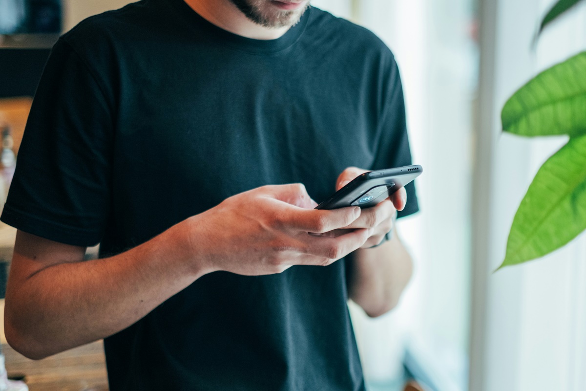 Foto colorida de homem branco mexendo no celular - limpo
