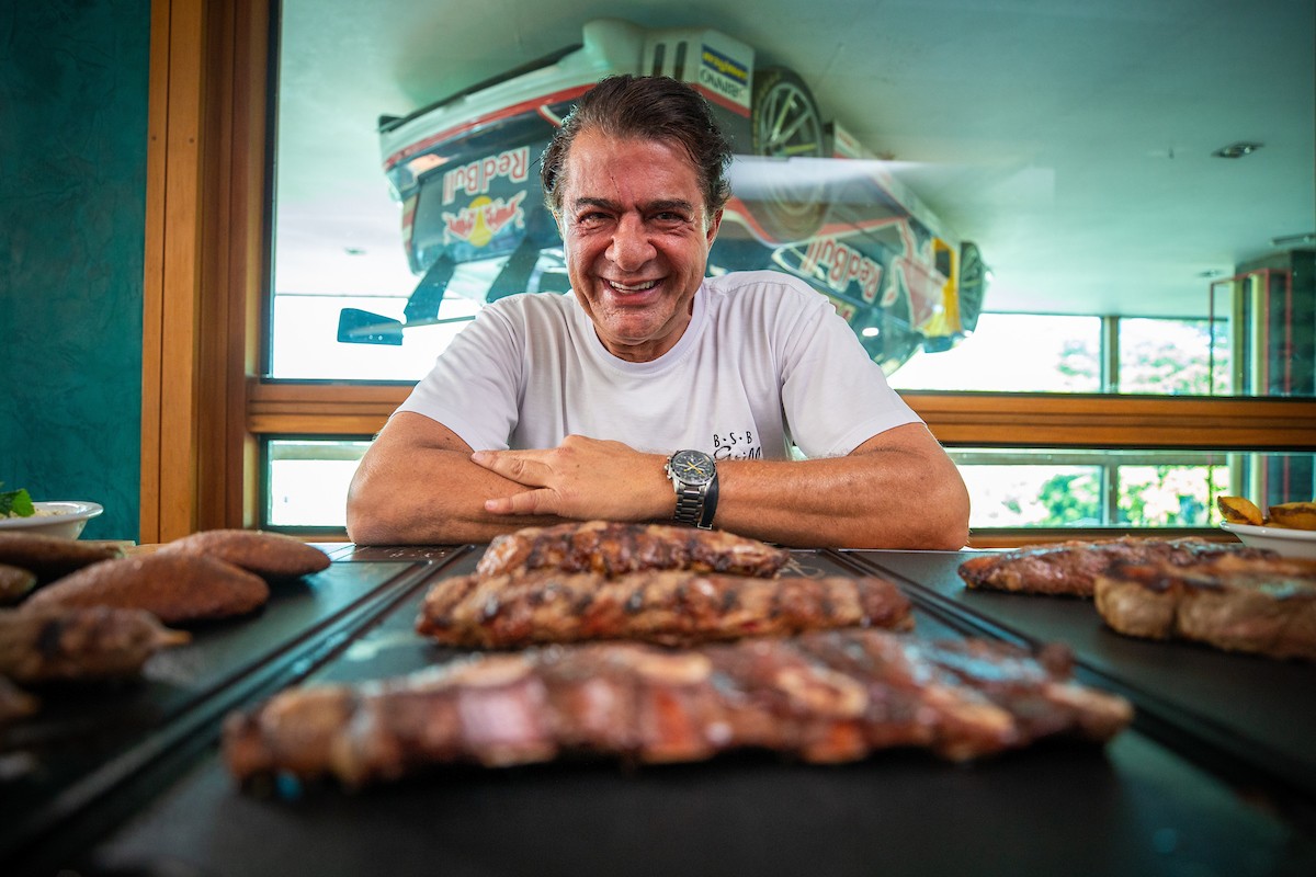 Fotografia colorida de homem posando na frente de mesa de carnes-Metrópoles
