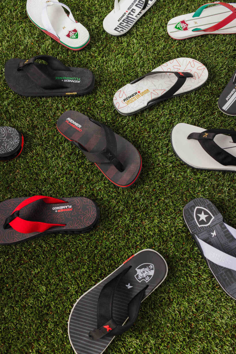 Diversas sandálias espalhadas no gramado. Cada modelo varia entre as cores preto, banco, vermelho e verde.