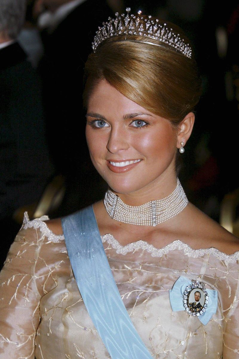 Foto colorida de mulher loira com tiara luxuosa e vestido de renda com uma faixa azul na diagonal - Metrópoles