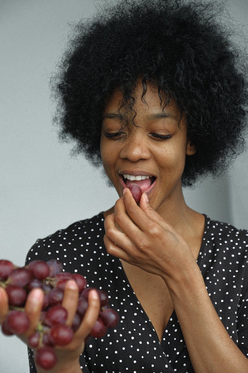 Jovem mulher negra comendo uvas - Metrópoles