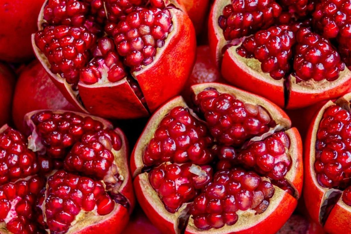 Foto colorida - Romã, fruta rica em nutrientes com uma coloração rosa e diversas sementes 