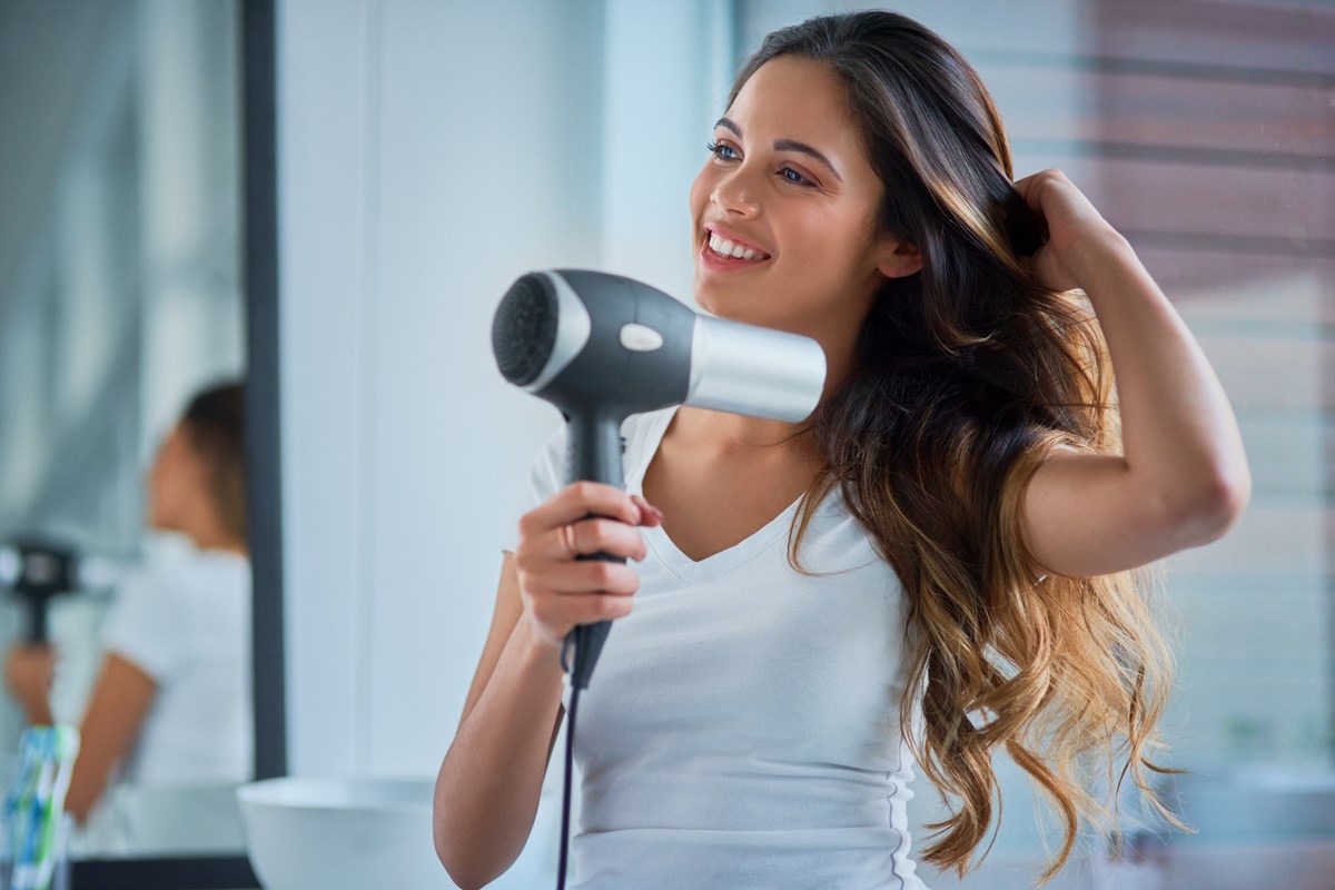 Foto colorida de mulher usando o secador no cabelo - Metrópoles