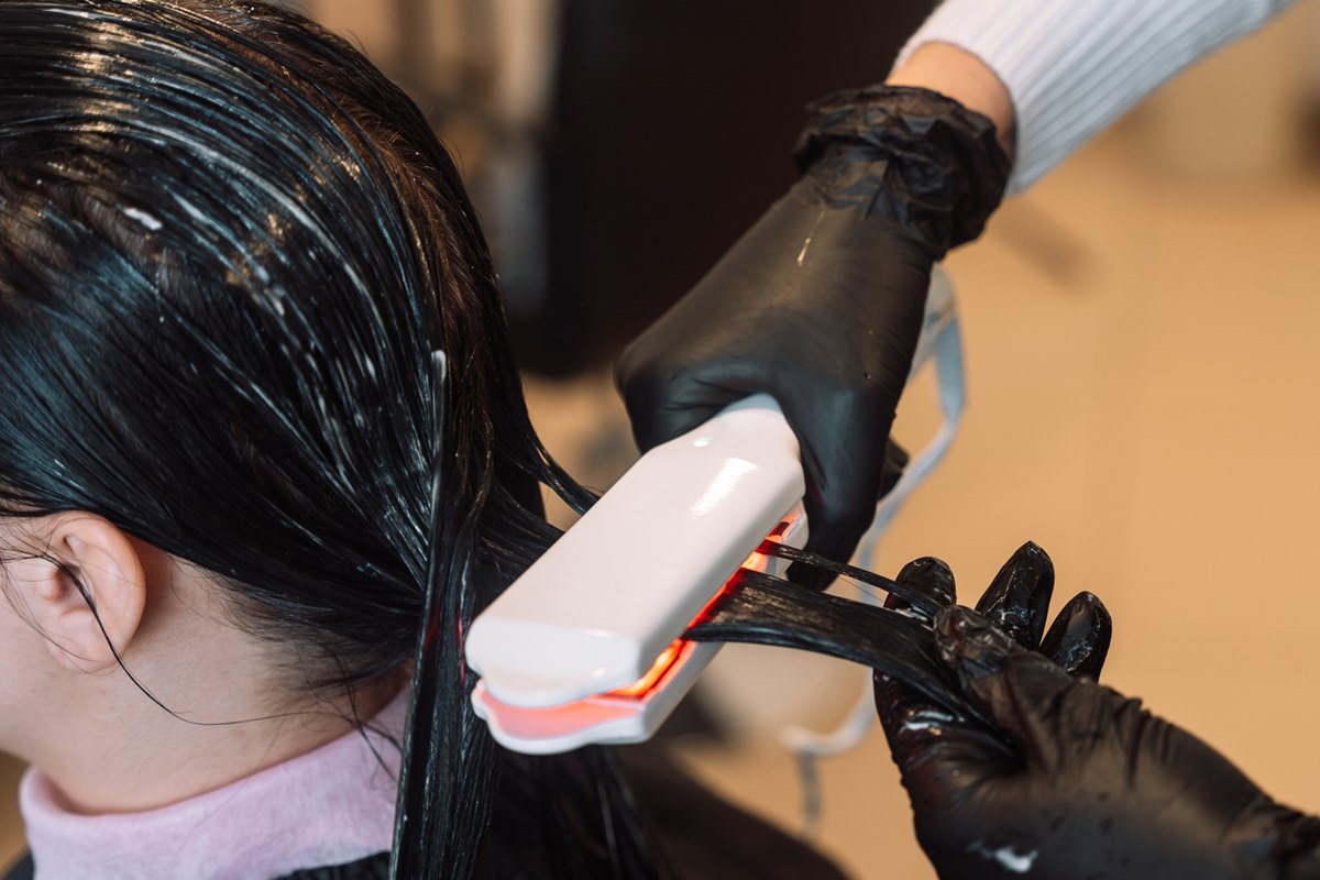 Foto colorida de chapinha sendo passada no cabelo molhado - Metrópoles