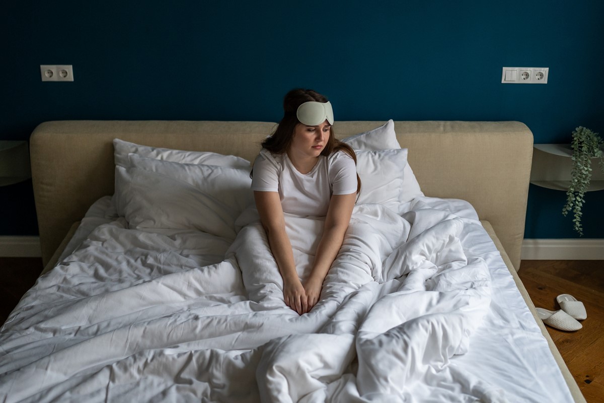 Foto colorida de mulher mulher sentada em uma cama - Metrópoles