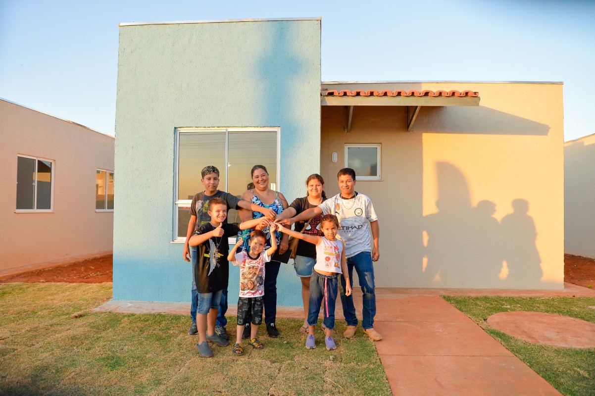 Fotografia colorida mostrando família com chave da casa nova-Metrópoles