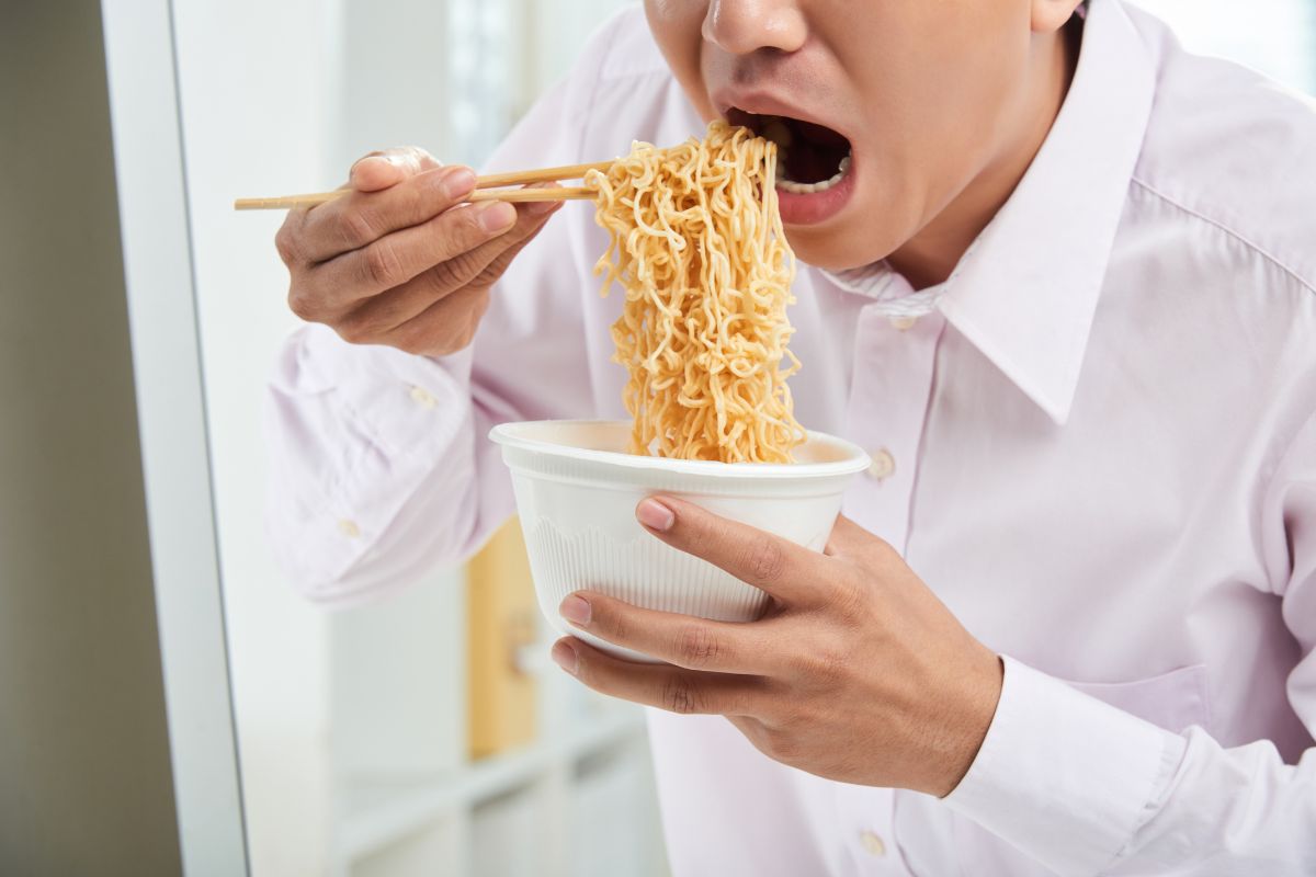 Foto colorida de um homem comendo macarrão - Metrópoles