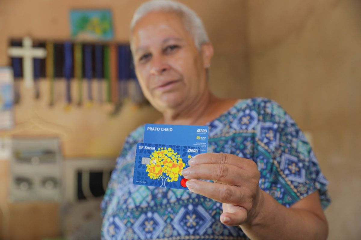 Fotografia colorida mostrando mulher segurando dois cartões-Metrópoles